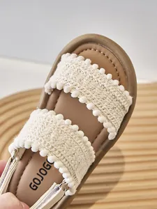 Primer plano detallado de las correas tejidas de sandalias étnicas para niñas con pompones