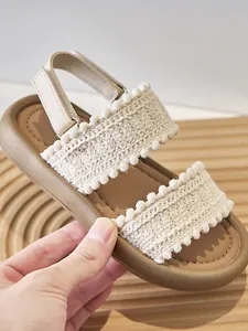 Detalle de sandalias de estilo étnico para niñas con tiras tejidas y suela marrón suave