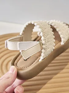 Vista detallada de sandalias étnicas de punto para niñas con pompones y velcro