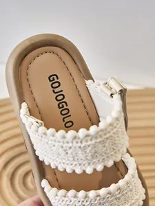 Detalle de sandalia de estilo étnico para niños con correa de ganchillo y pompones