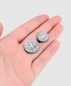 Detailed macro view of vintage silver metal eagle buttons resting on a palm for scale.
