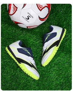 Vue détaillée de chaussures de football pour enfants avec velcro sur gazon vert professionnel