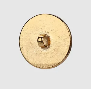 Macro detail showing the back of a textured gold metal clothing button with shank loop