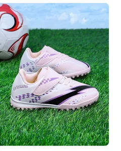 Détail de profil des chaussures de football roses pour enfants sur gazon avec velcro.