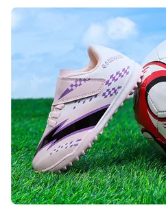 Vue détaillée de chaussures de football pour enfants roses avec scratch sur gazon vert