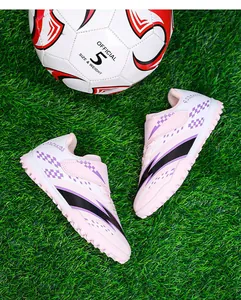 Chaussures de football roses pour enfants avec velcro sur un terrain de gazon