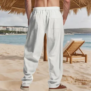 Back view of white linen men's loose casual straight-leg trousers on a scenic beach setting