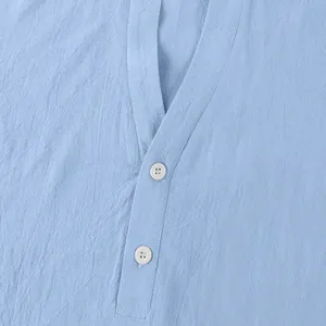 Close-up of light blue linen shirt featuring stand collar and white button details.
