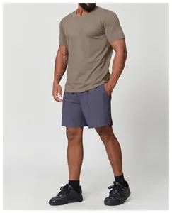 Athletic male model wearing a tan quick-drying sports T-shirt and greyish shorts