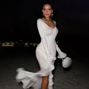 Elegant white long-sleeved V-neck dress with ruffled slit shown in night beach setting
