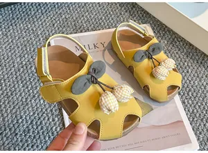 Nahaufnahme von gelben Kleinkindersandalen mit einer hübschen Tulpenverzierung.