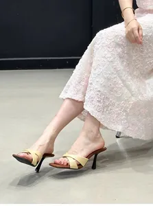 Primer plano de sandalias beige de tacón alto con tiras cruzadas y vestido de encaje