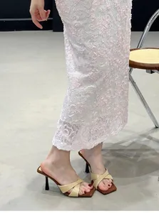 Elegantes sandalias de tacón alto con tiras cruzadas usadas con una falda rosa
