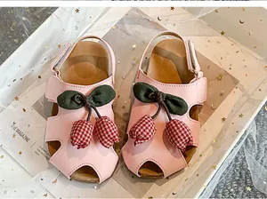 Detail der rosa Mädchensandalen mit rot karierter Tulpendekoration und Hohlraumdesign