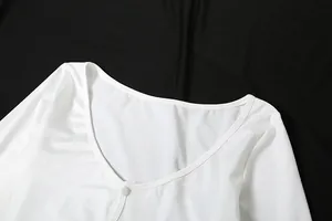 Close-up detail of a white V-neckline with a small button on a long sleeve dress
