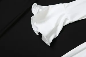 Close-up detail of white long sleeve dress featuring elegant flared ruffle cuffs on black.