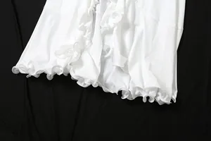 Detailed view of the elegant white ruffled hem on this summer V-neck slim slit dress