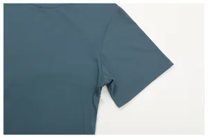 Close-up of the shoulder and sleeve seam on a teal quick-dry athletic T-shirt.