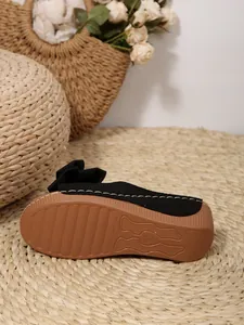 Detailed view of women's black bow platform slides with non-slip wedge sole.