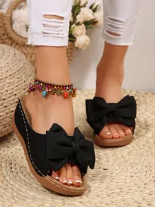 Close-up of the elegant bow detail on a black platform slide sandal for summer.