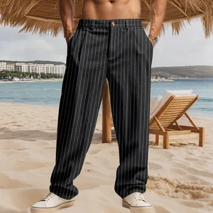 Full shot of black pinstriped linen casual trousers worn by a man on a sunny beach.