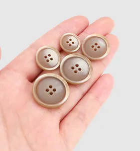 Detail of assorted size brown resin buttons held in hand for scale and texture