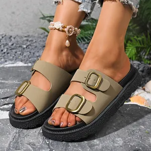 Close-up of stylish women's khaki double buckle platform sandals outdoors on grey rocks.