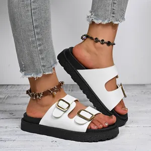 On-foot view of white platform sandals with double gold buckles and black thick soles