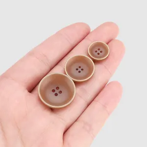 Set aus drei matten braunen Harzknöpfen für hochwertige Kleidung, auf der Handfläche gezeigt