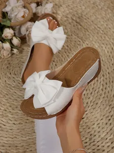 Detailed view showing the textured white bow and platform sole of these summer wedge sandals