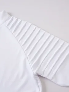 Gros plan détaillé du tee-shirt de sport blanc à manches longues avec design plissé à l'épaule.