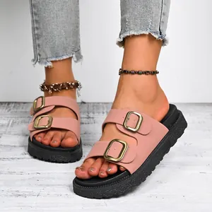 Close-up of pink double-strap slides for women with gold buckles and platform black soles