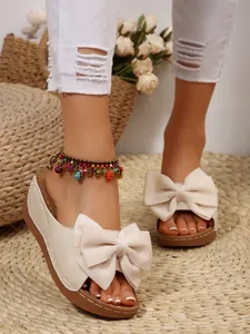 Close-up of stylish cream wedge sandals with a large decorative bow for summer.