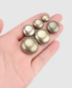 Macro view of premium brass metal buttons in various sizes held in a human palm