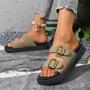 Close-up of khaki double-buckle platform slides for women on a stone surface