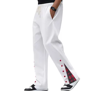 Dettaglio dei pantaloni sportivi bianchi da uomo con spacco laterale e fodera tartan