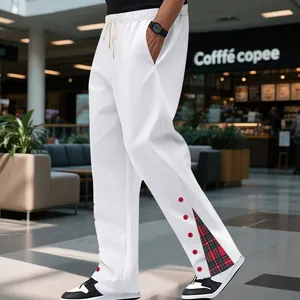 Dettaglio dei pantaloni sportivi bianchi da uomo con inserto scozzese rosso.