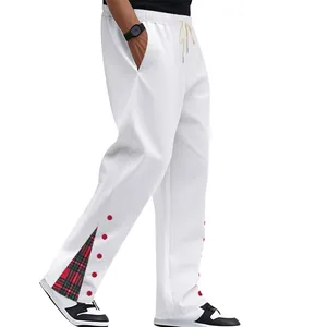Dettaglio dei pantaloni sportivi pesanti bianchi da uomo con inserto scozzese e bottoni