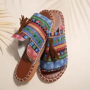 Flache Pantoletten für Damen im Boho-Stil mit buntem Webmuster und braunen Quasten.