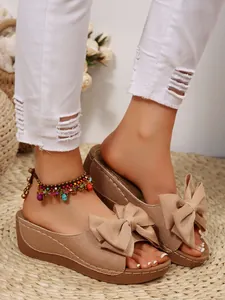 Close-up detail of stylish textured beige wedge sandals with a large bow on top