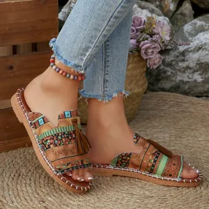 Detailaufnahme von flachen Boho-Sandalen mit ethnischen Mustern und braunen Quasten