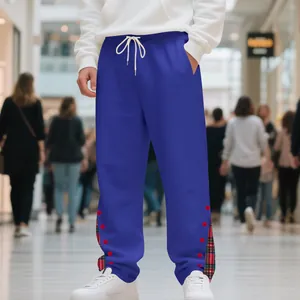 Dettaglio dei pantaloni sportivi blu pesanti con inserti scozzesi alla caviglia.