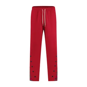 Dettaglio dei pantaloni sportivi rossi da uomo con bordo a quadri e bottoni laterali.