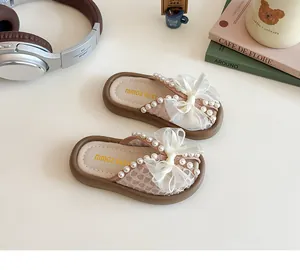 Vista detallada de zapatillas de malla rosa para niñas con perlas y un lazo de tul.