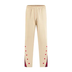 Vista dei pantaloni della tuta beige da uomo con inserti scozzesi e bottoni rossi