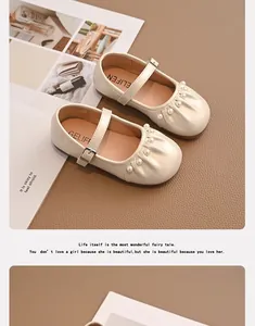 Detalle de merceditas beige para niña con adornos de perlas y suela blanda.