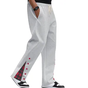 Dettaglio pantaloni grigi con spacco laterale, fodera a quadri e punti rossi decorativi.