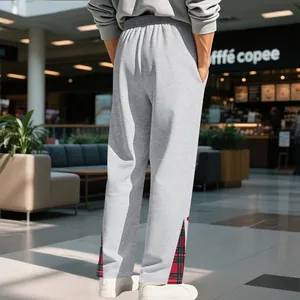 Vista dettagliata dei pantaloni sportivi grigi da uomo con inserti scozzesi rossi sul fondo