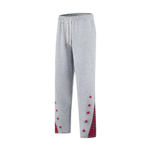 Dettaglio pantaloni sportivi grigi da uomo con inserto scozzese rosso e bottoni