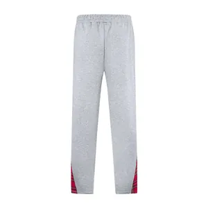Dettaglio di pantaloni sportivi grigi con pannello a contrasto a quadri rossi sul fondo